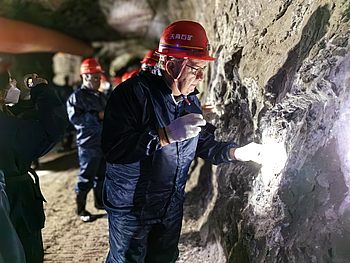 Mann mit Helm leuchtet unter Tage an die Wand 